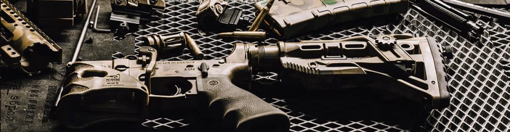 Fusil démonté sur une table à mailles métalliques.