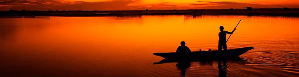 Bateau sur lac au coucher de soleil rouge
